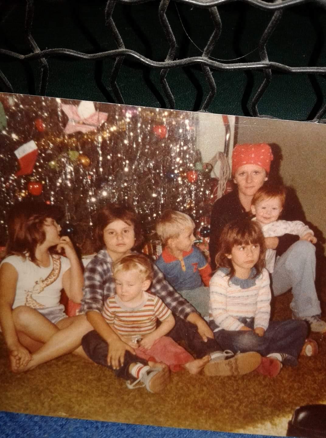 A group of children sitting in front of a christmas tree
