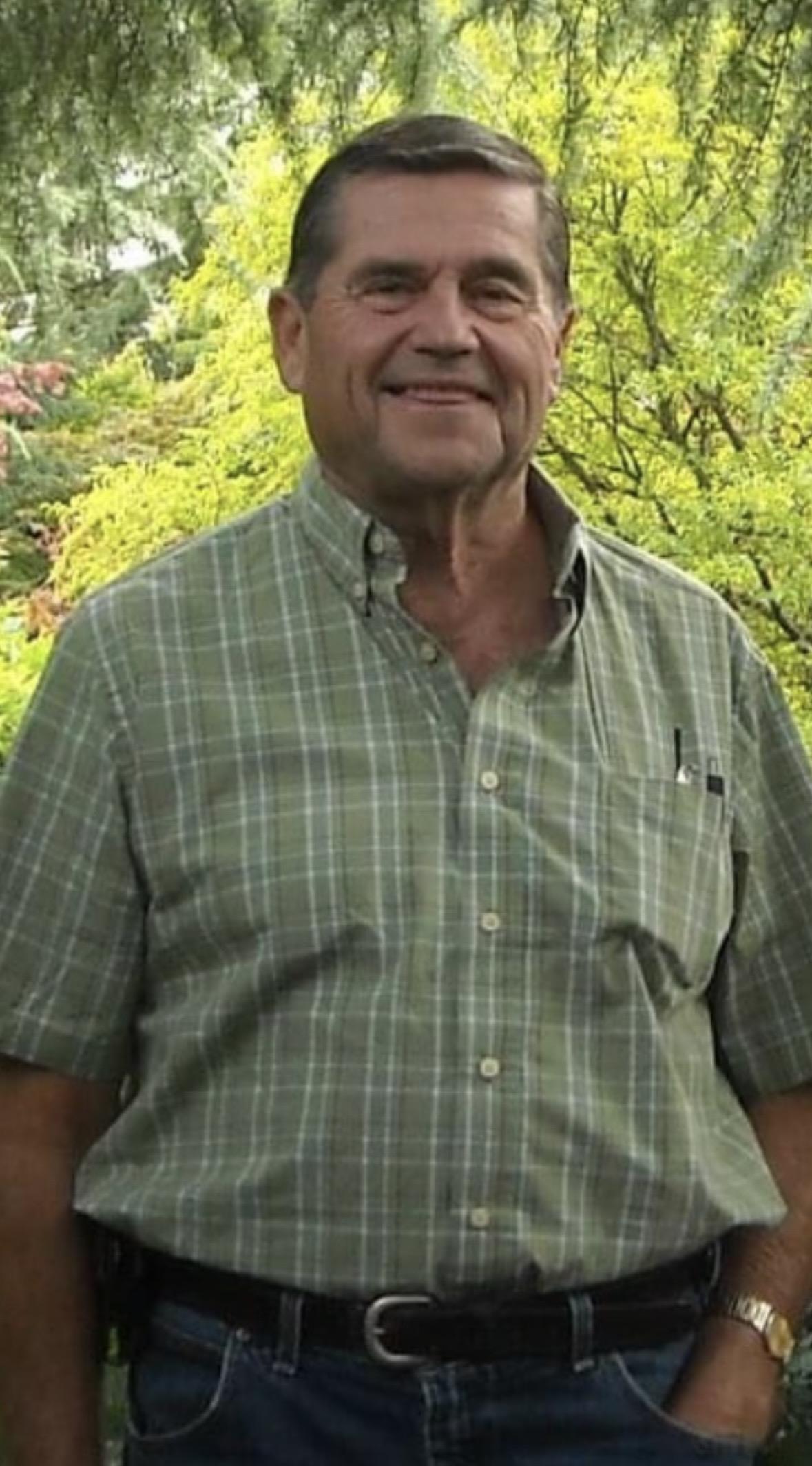 A man standing outside in front of trees