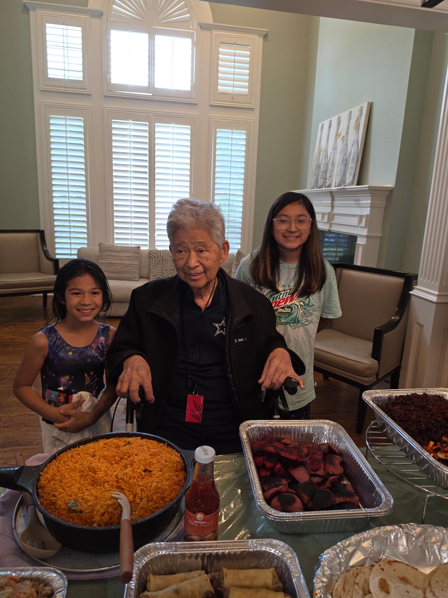 A group of people standing next to a table full of food