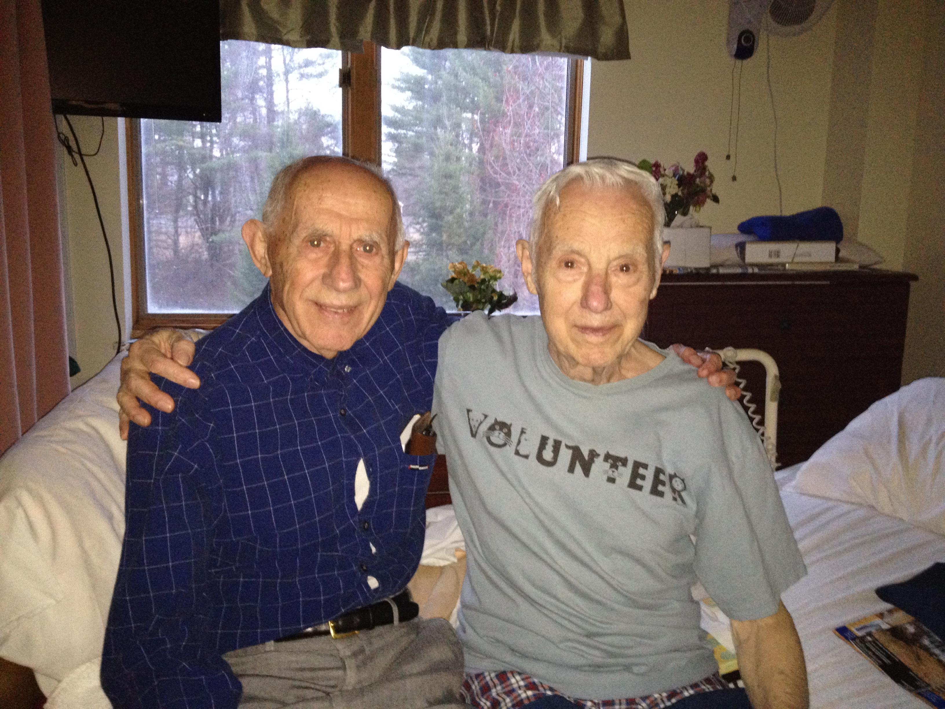 Two old men sitting on a bed