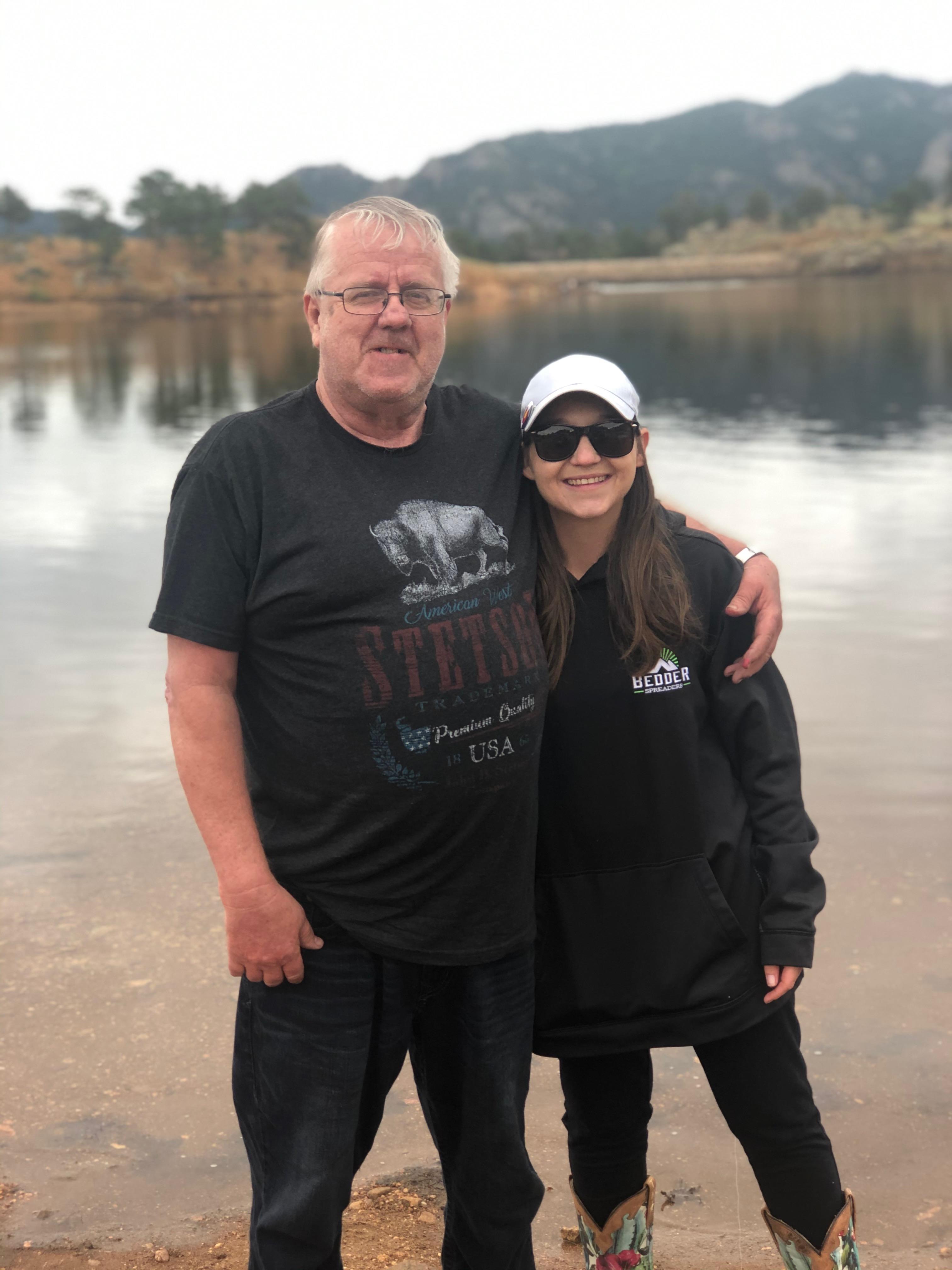 A man and woman standing in front of a lake