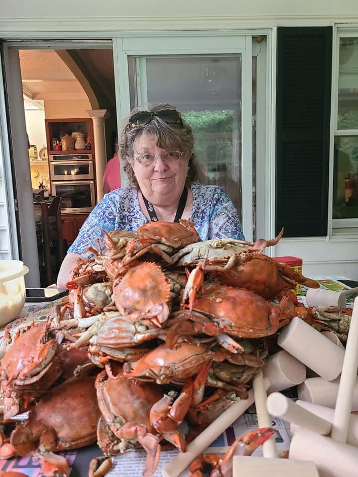 A woman sitting in front of a large pile of crabs