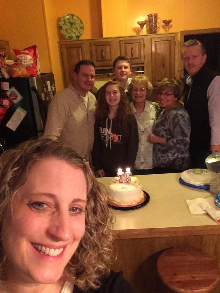 A group of people standing around a cake