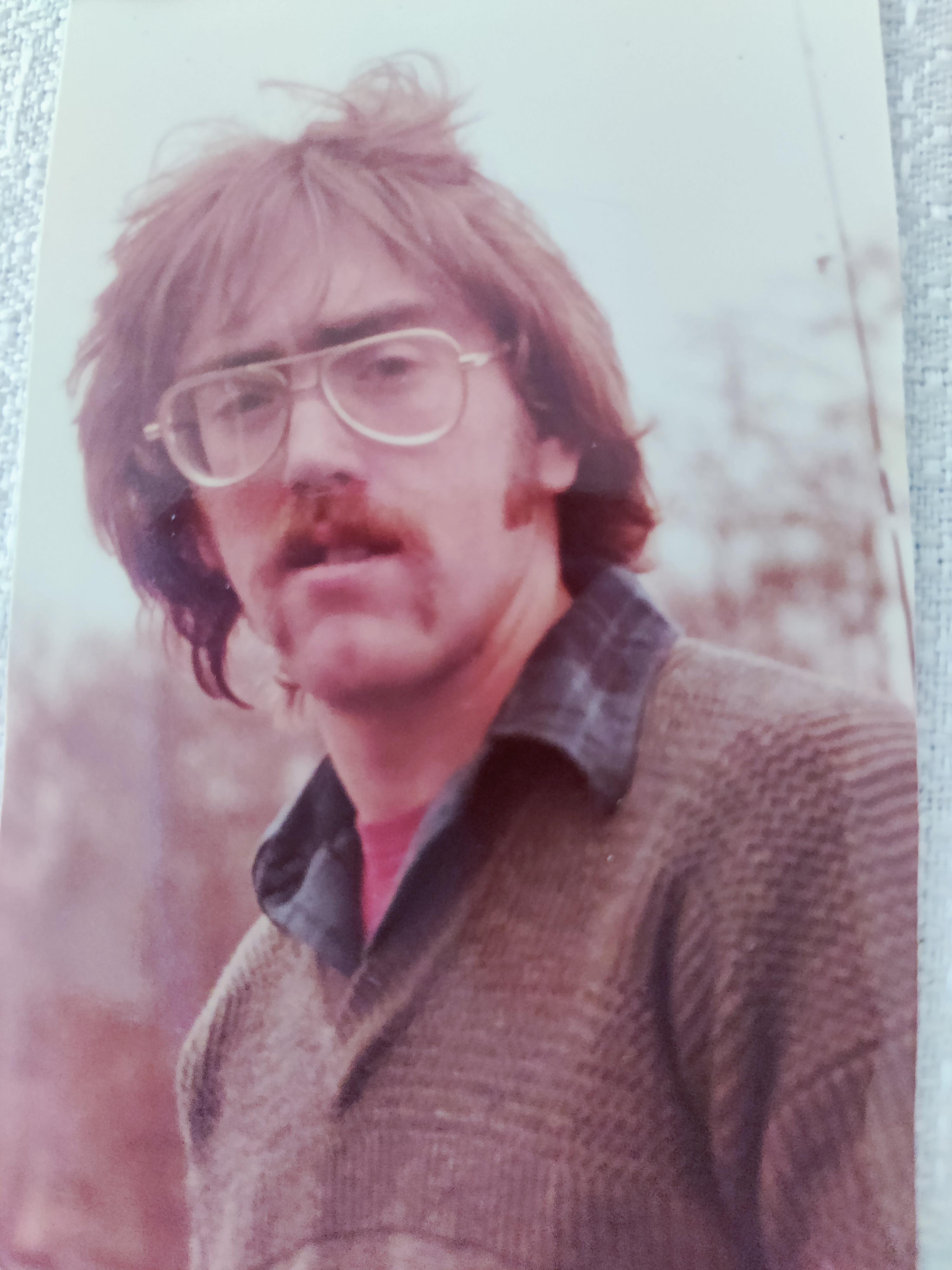 A man with long hair and mustache wearing glasses