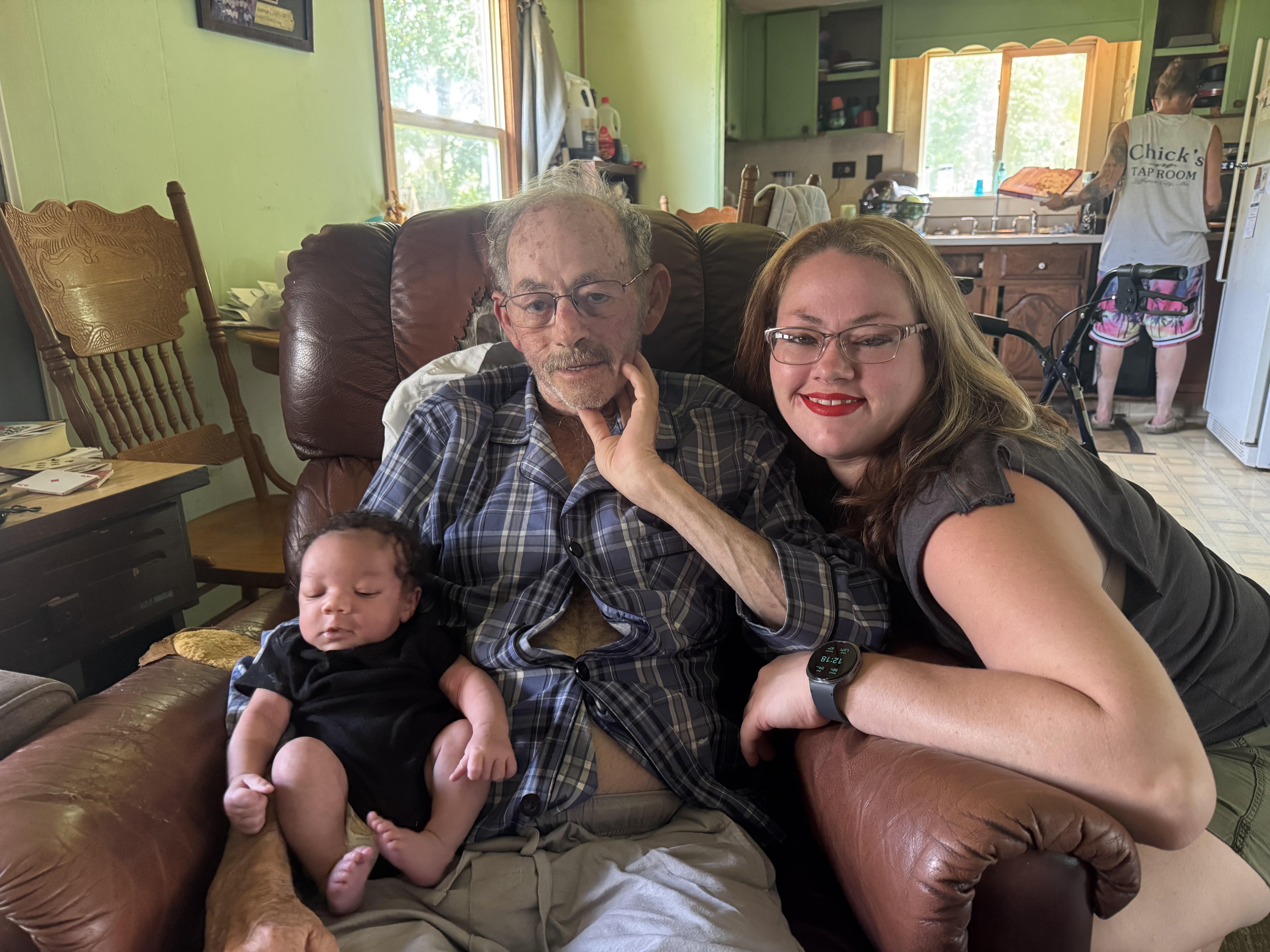 A man and woman sitting on a couch with a baby