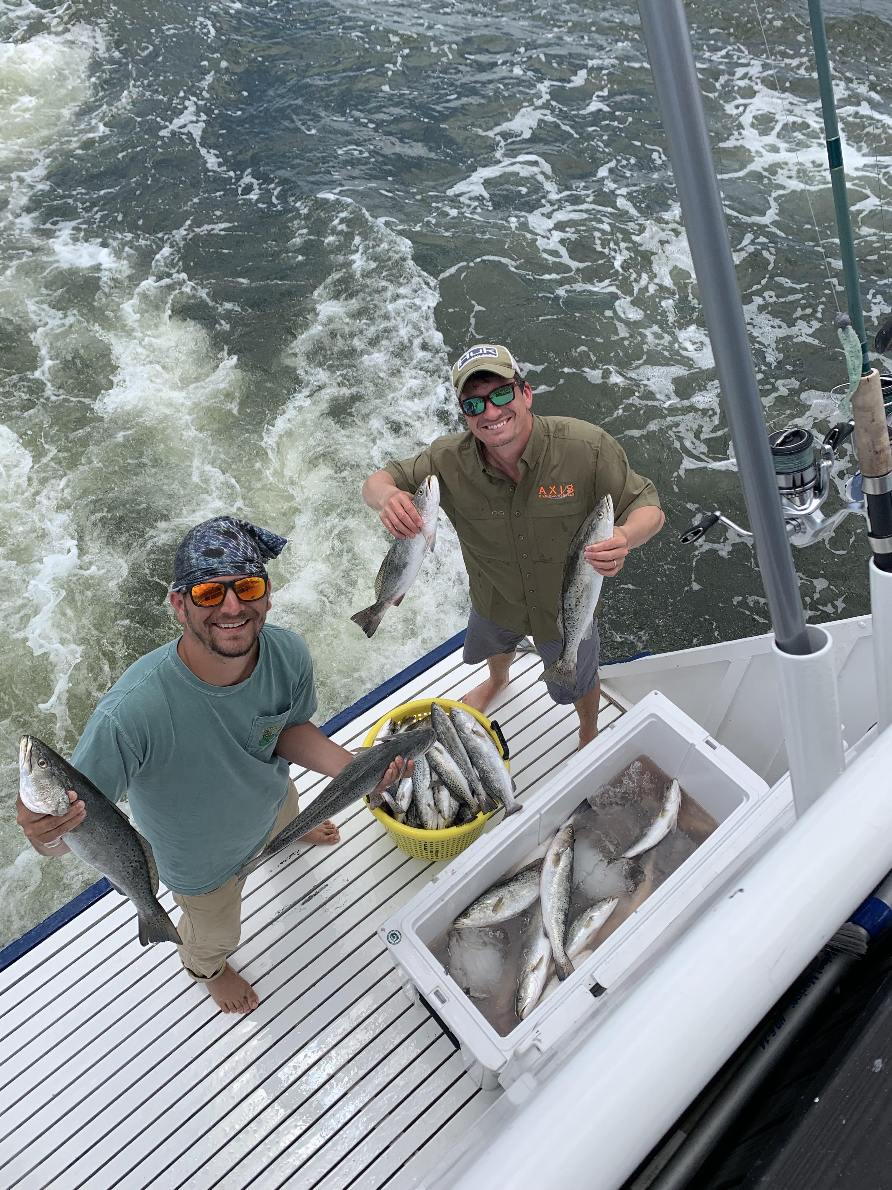 Two men holding fish on a boat