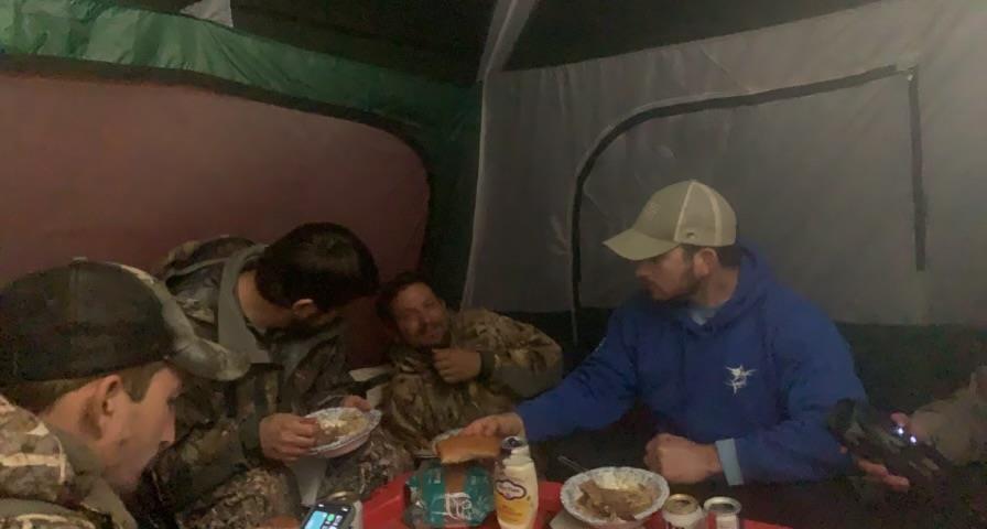A group of men eating in a tent