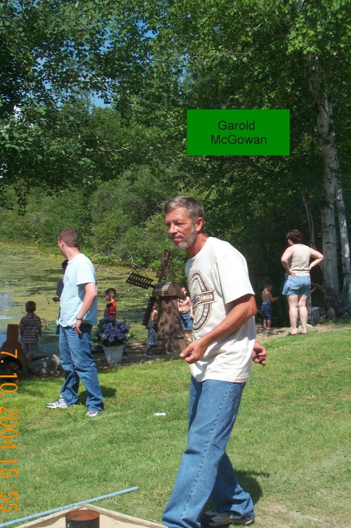A man in a white shirt and blue jeans standing in a grassy area