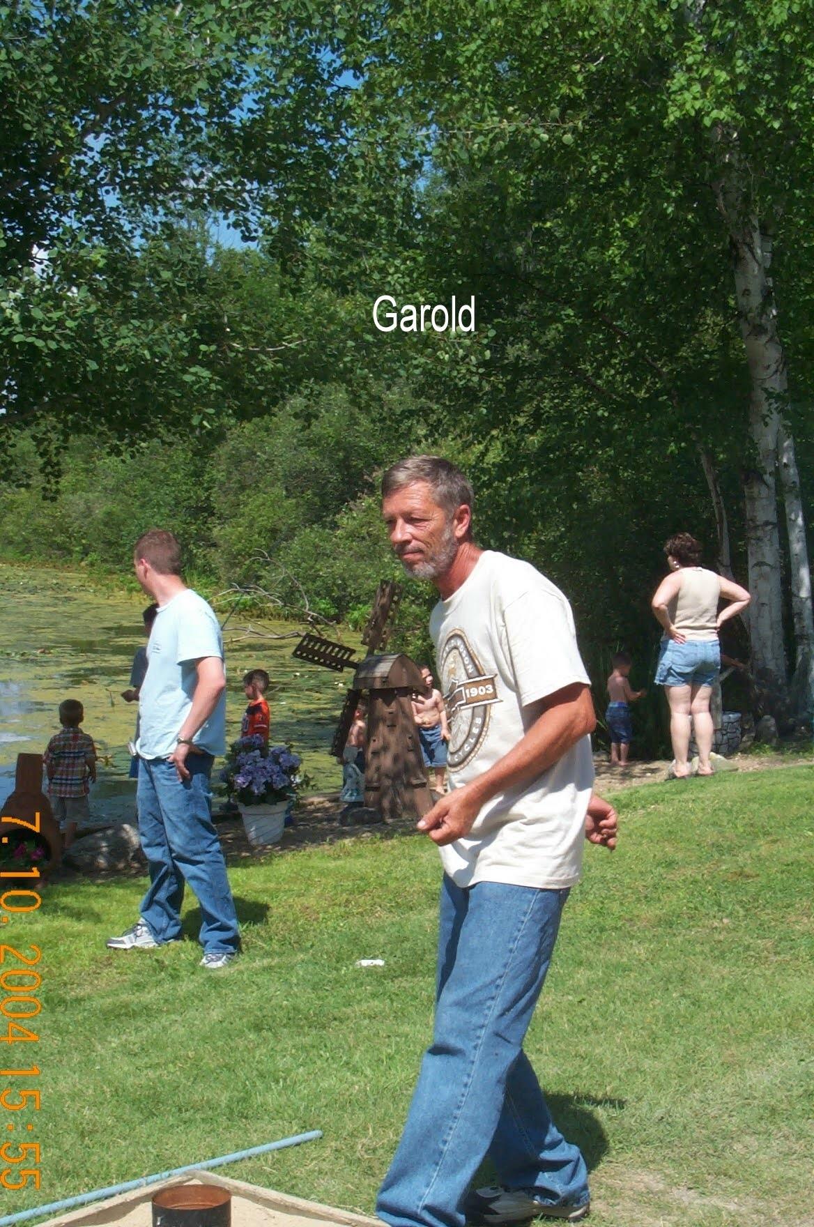 A man in a white shirt and blue jeans standing in a grassy area