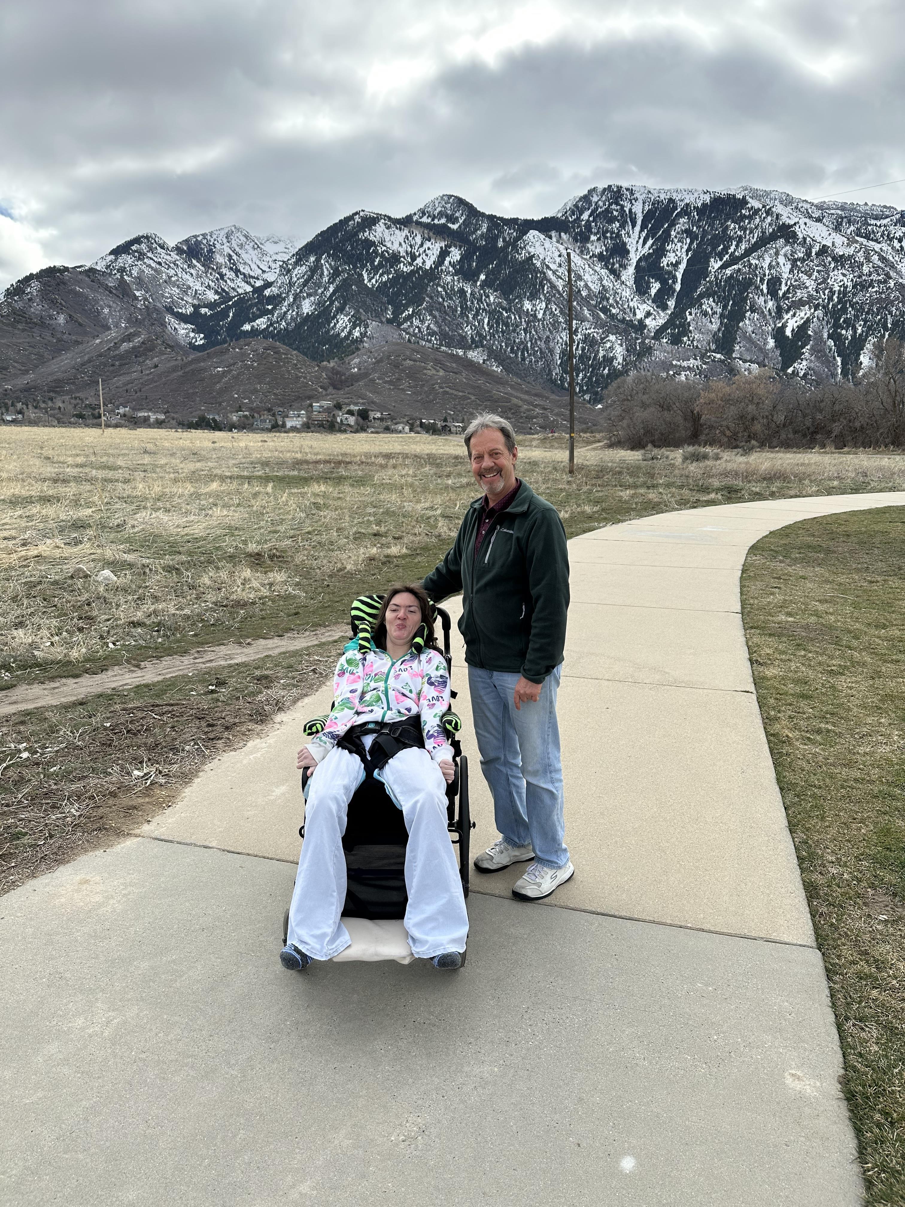 A man standing next to a woman in a wheelchair