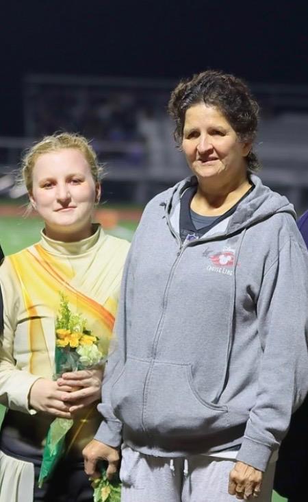 A woman standing next to a woman holding a bouquet of flowers