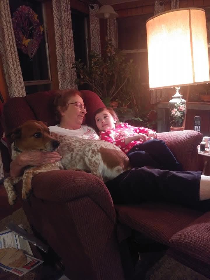 A woman and child sitting on a couch with a dog