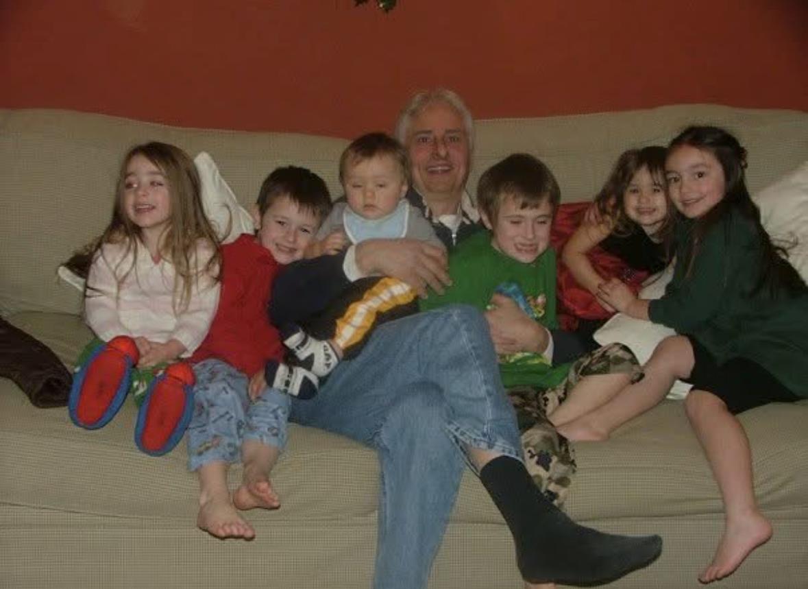 A man sitting on a couch with several children
