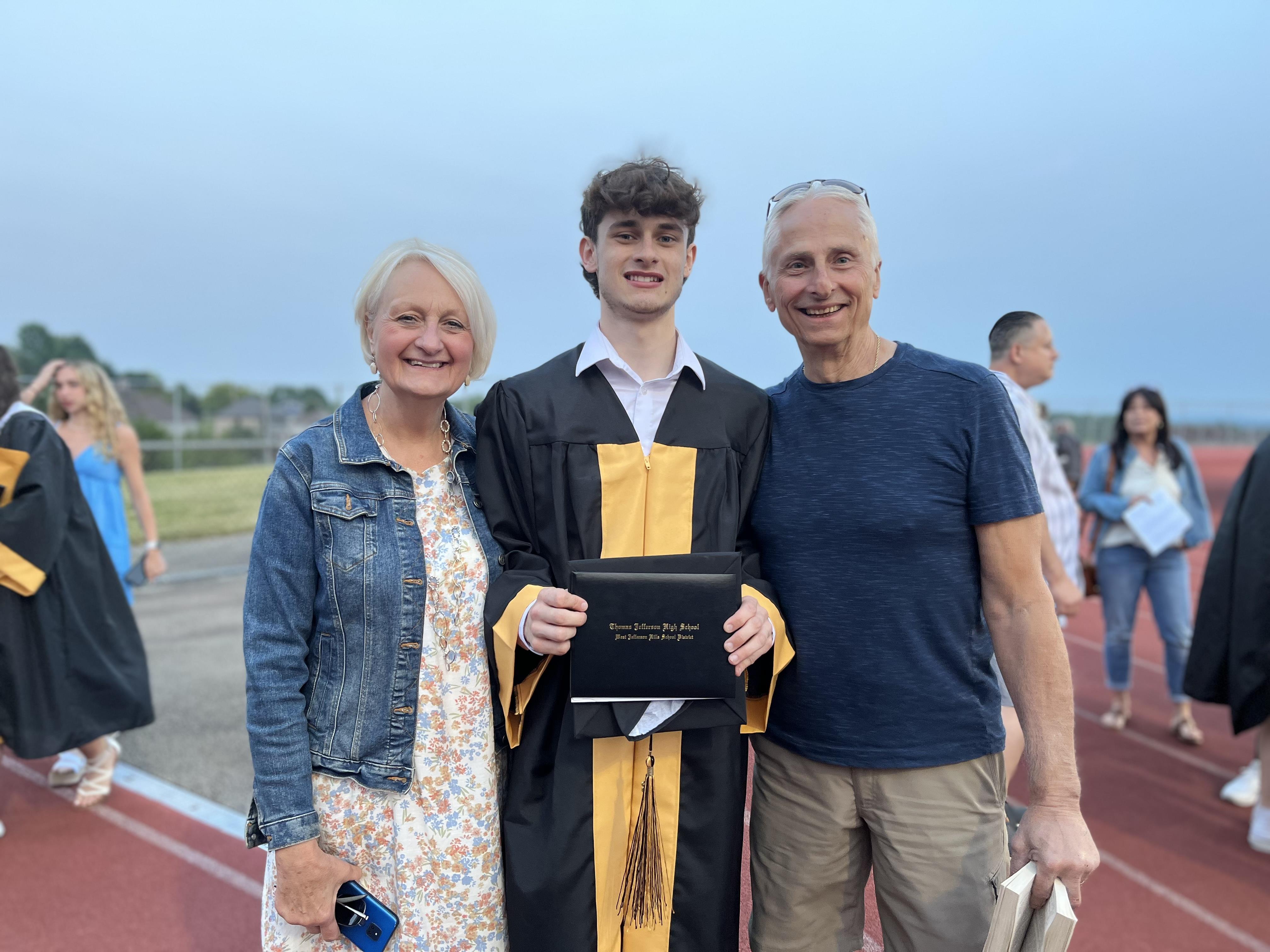 A man and woman standing next to a man holding a diploma