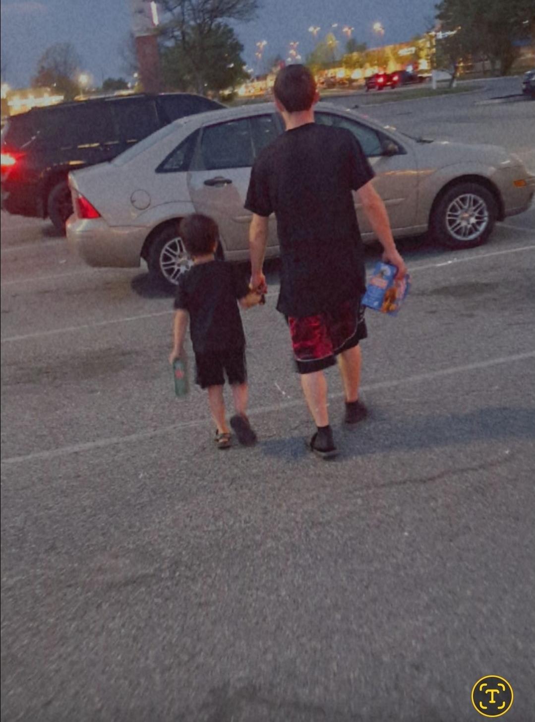 A man and child walking in a parking lot