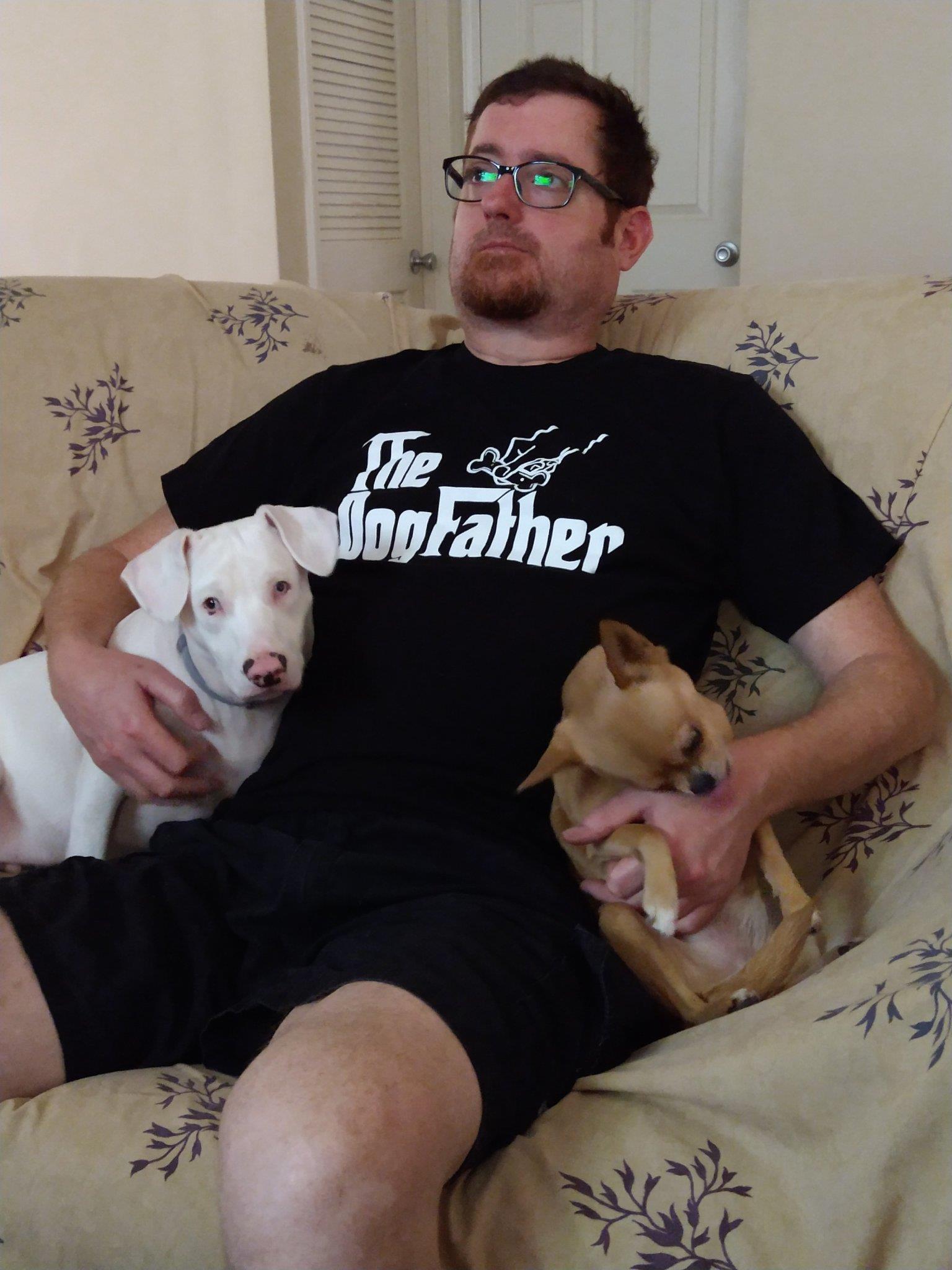 A man sitting on a couch with two dogs