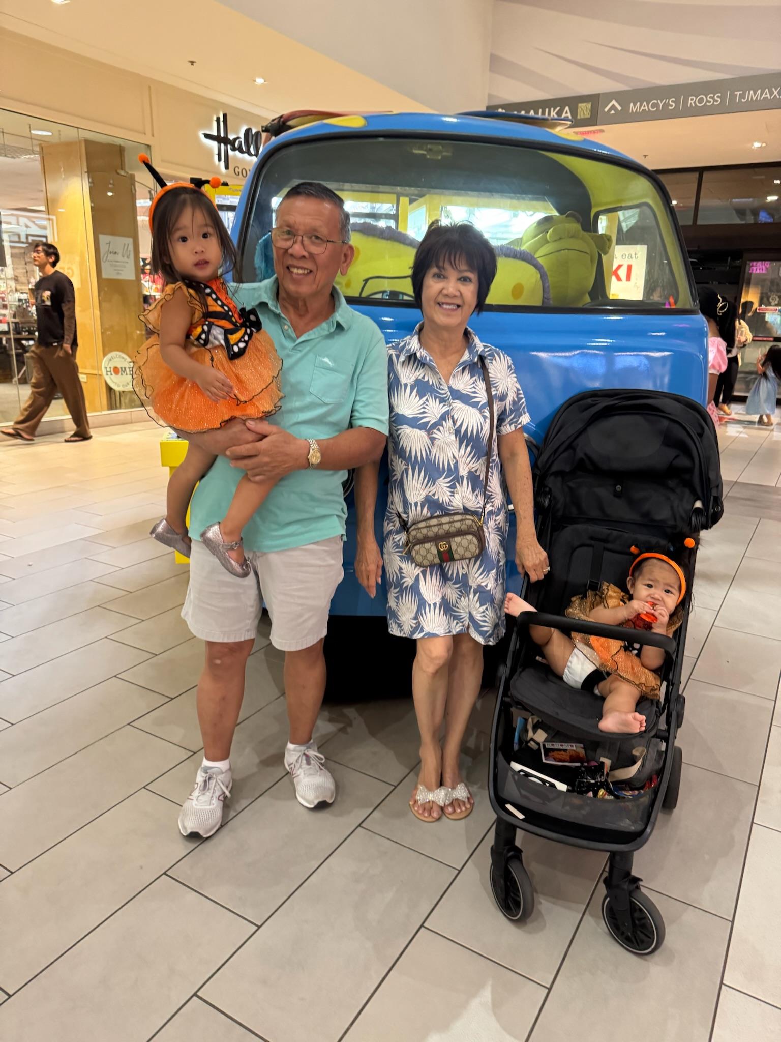 A man and woman standing next to a baby in a car