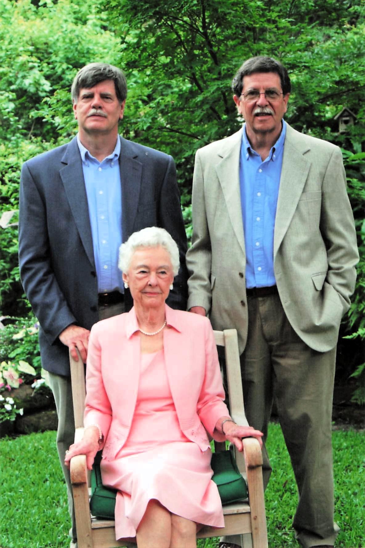 A group of men standing next to a woman in a chair
