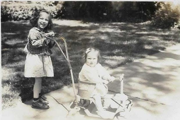A girl standing next to a baby on a stroller
