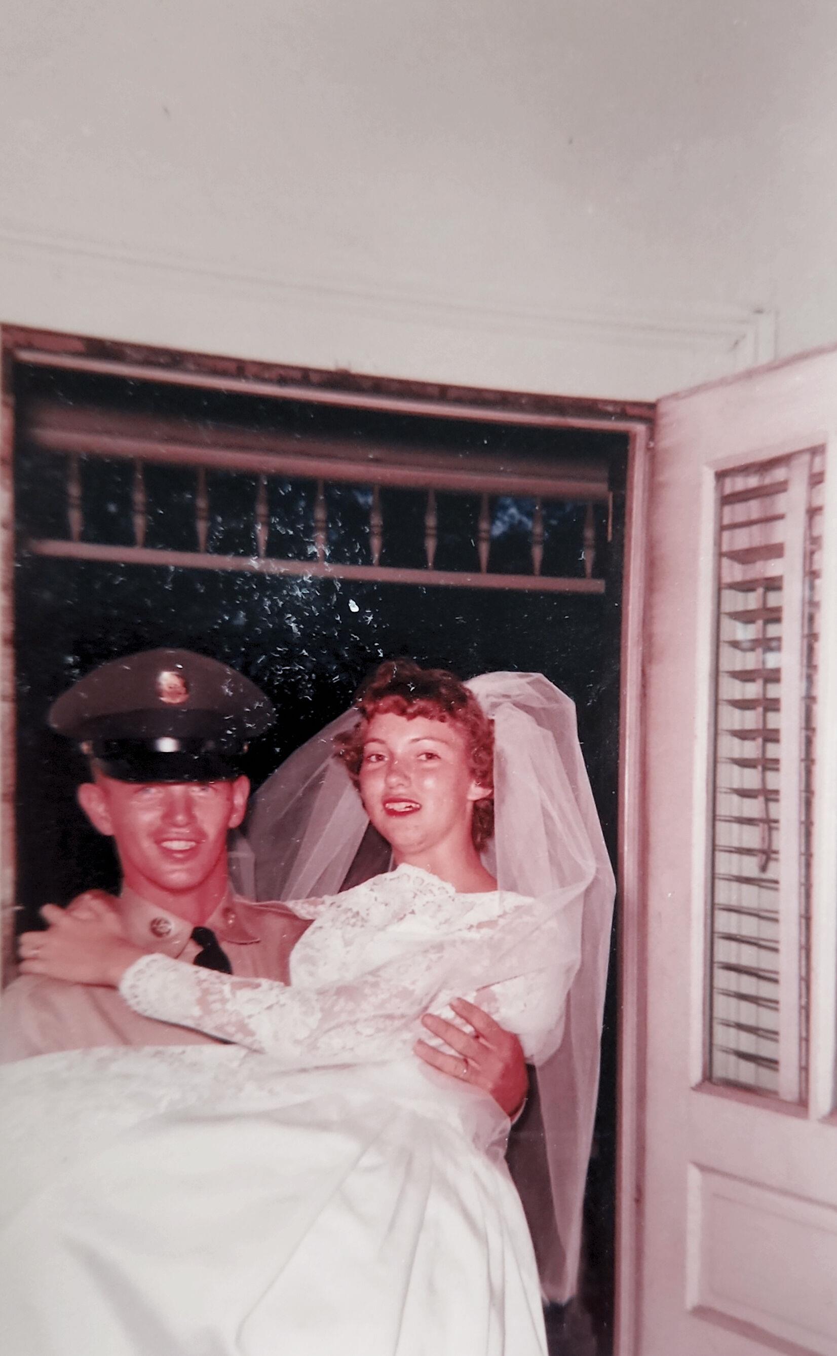 A man holding a woman in a wedding dress