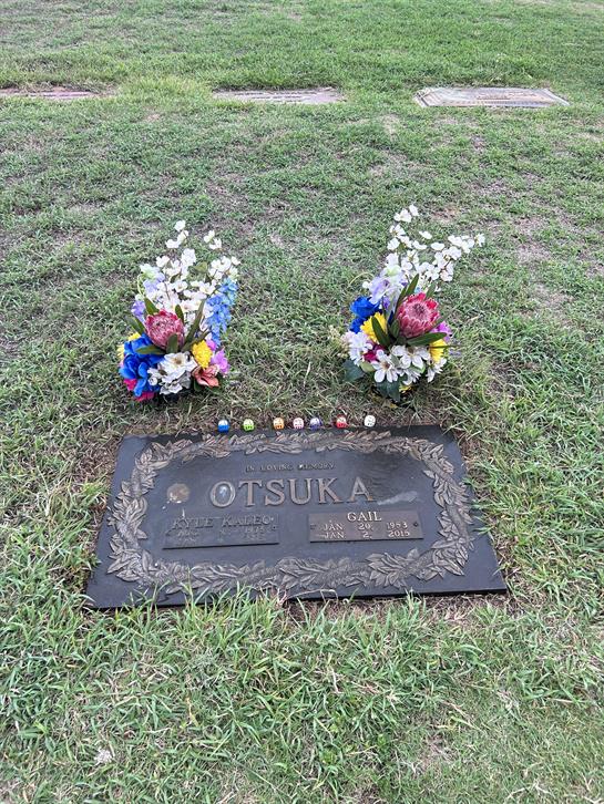 A grave marked Otsuka adorned with vibrant flowers and decorations, set in a tranquil cemetery.