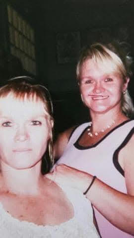 Two women share a joyful moment while posing together, smiling brightly in a relaxed atmosphere.